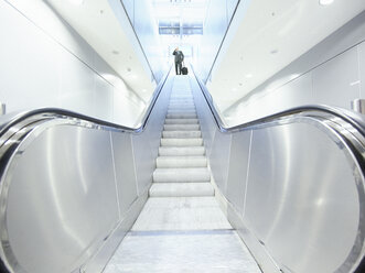 Businessman with briefcase on escalator - STKF000275