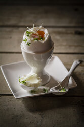 Cracked egg in egg cup with cress and spoon, close up - SBDF000066