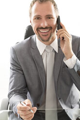 Deutschland, Porträt eines Geschäftsmannes, der lächelnd mit einem Mobiltelefon spricht - MAEF006637