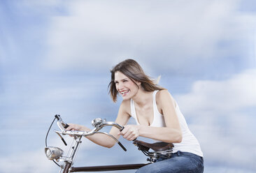 Germany, Cologne, Young woman riding bicycle, smiling - FMKF000830