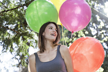 Deutschland, Köln, Junge Frau mit Luftballons, lächelnd - FMKF000813