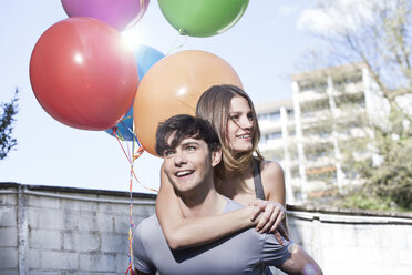 Germany, Cologne, Young man giving piggyback ride to woman, smiling - FMKF000814