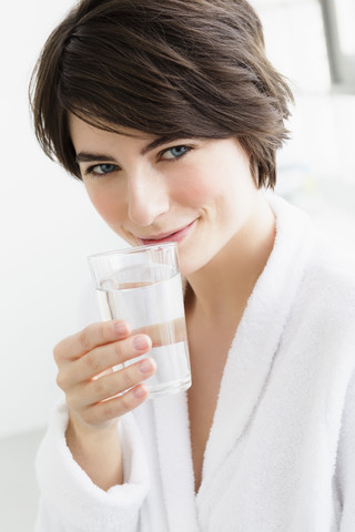 Deutschland, Bayern, München, Porträt einer jungen Frau mit Wasserglas, Nahaufnahme, lizenzfreies Stockfoto