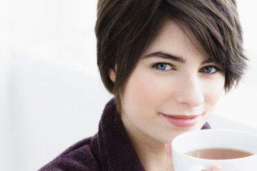 Germany, Bavaria, Munich, Portrait of young woman holding tea cup, close up - SPOF000390