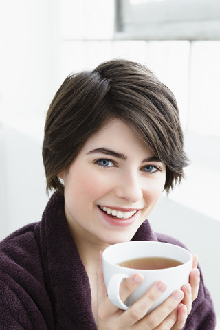 Deutschland, Bayern, München, Porträt einer jungen Frau mit Teetasse, Nahaufnahme, lizenzfreies Stockfoto