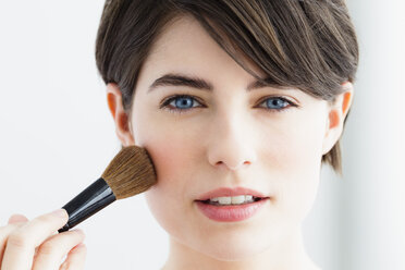 Germany, Bavaria, Munich, Young woman using blusher brush, close up - SPOF000409