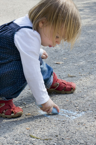 Germany, Little girl using chalk stock photo