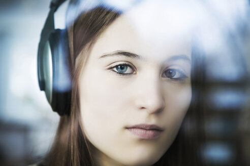 Deutschland, Köln, Porträt eines Teenagers, der mit Kopfhörern Musik hört, Nahaufnahme - JAT000007
