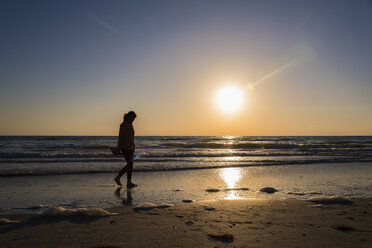 USA, Florida, Indian Rocks Beach, Ältere Frau läuft bei Sonnenuntergang am Strand - ABAF000839