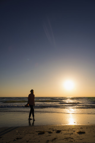 USA, Florida, Indian Rocks Beach, Ältere Frau läuft bei Sonnenuntergang am Strand, lizenzfreies Stockfoto