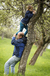 Deutschland, Baden Württemberg, Vater hilft Tochter beim Klettern auf Baum - SLF000136
