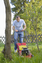 Deutschland, Kaufbeuren, Mittlerer Erwachsener Mann bei der Gartenarbeit mit Rasenmäher - CAF000009