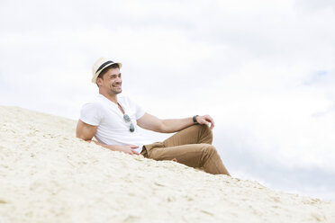 Deutschland, Bayern, Porträt eines jungen Mannes im Sand liegend, lächelnd - MAEF006760