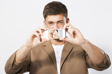 Junger Mann zeigt Bild mit Smartphone, Nahaufnahme - MAEF006801