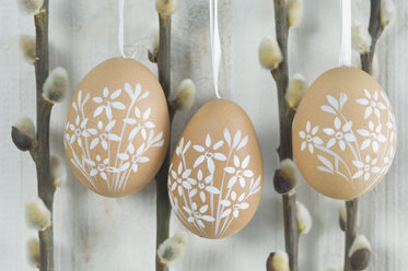 Painted easter eggs hanging on wooden wall - ASF004969