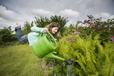 Germany, Bavaria, Kaufbeuren, Mid adult woman watering plants in garden - CAF000014