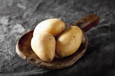 Raw potatoes on wooden spoon, close up - CSF019395