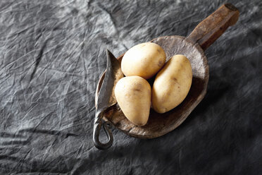 Raw potatoes on wooden spoon, close up - CSF019394