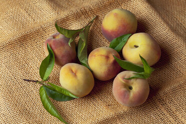 Peaches on leaves on sack, close up - CSF019363