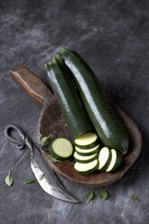 Courgette on wooden spoon with knife on black textile, close up - CSF019357