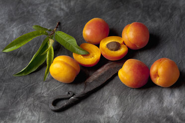 Apricots with leaves and knife on black textile, close up - CSF019353