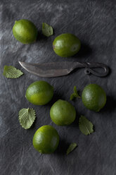 Limes with leaves and knife on black textile, close up - CSF019349