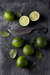 Limes with leaves and knife on black textile, close up - CSF019348