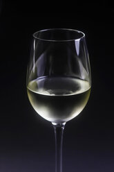 Glas Weißwein vor schwarzem Hintergrund, Nahaufnahme - JTF000417