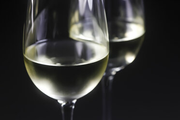 Gläser mit Weißwein vor schwarzem Hintergrund, Nahaufnahme - JTF000418