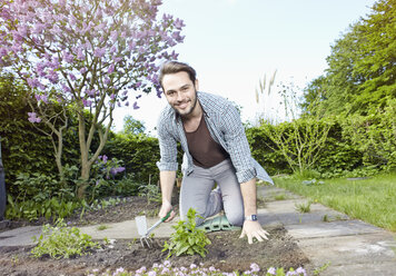 Deutschland, Köln, Porträt eines jungen Mannes bei der Gartenarbeit, lächelnd - RHYF000414