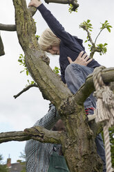 Deutschland, Köln, Vater hilft Sohn beim Klettern auf Baum - RHYF000386