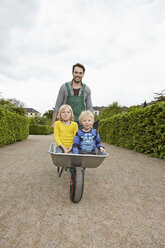 Germany, Cologne, Father carrying son in wheelbarrow, smiling - RHYF000381