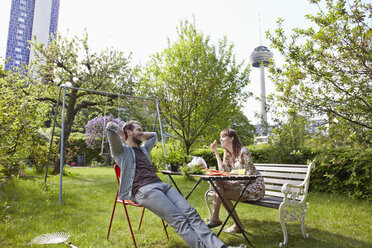 Deutschland, Köln, Junges Paar beim Frühstück im Garten, lächelnd - RHYF000454