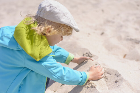 Deutschland, Mecklenburg Vorpommern, Junge spielt mit Sand an der Ostseeküste - MJF000185