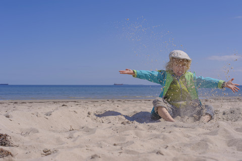 Deutschland, Mecklenburg Vorpommern, Junge spielt mit Sand an der Ostseeküste, lizenzfreies Stockfoto