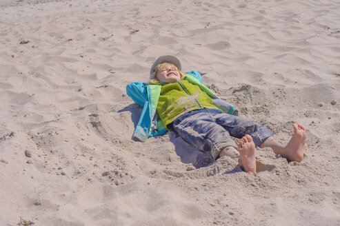 Deutschland, Mecklenburg Vorpommern, Junge entspannt sich auf Sand an der Ostsee - MJF000190