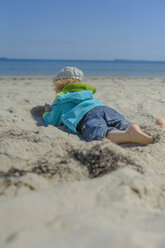 Deutschland, Mecklenburg Vorpommern, Junge entspannt sich auf Sand an der Ostsee - MJF000171