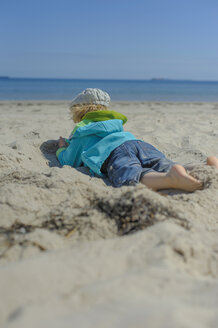 Deutschland, Mecklenburg Vorpommern, Junge entspannt sich auf Sand an der Ostsee - MJF000171