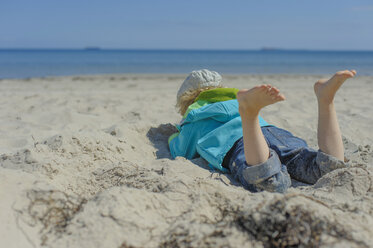 Deutschland, Mecklenburg Vorpommern, Junge entspannt sich auf Sand an der Ostsee - MJF000170