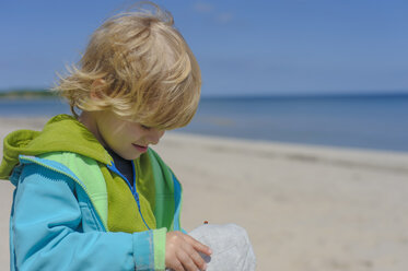 Deutschland, Mecklenburg Vorpommern, Junge schaut auf Mütze am Strand - MJF000169