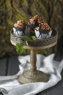 Mit Schokoladenbuttercreme überzogene Cupcakes und mit Hirschen verzierte Verpackungen auf einem Tortenständer - ECF000181