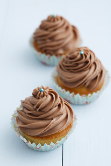 Mit Schokoladenbuttercreme überzogene Cupcakes auf Holztisch, Nahaufnahme - ECF000178