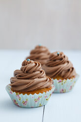 Mit Schokoladenbuttercreme überzogene Cupcakes auf Holztisch, Nahaufnahme - ECF000177