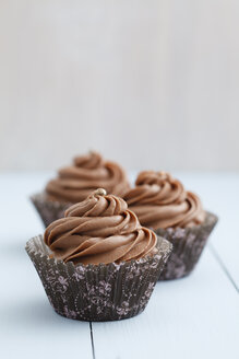 Mit Schokoladenbuttercreme überzogene Cupcakes auf Holztisch, Nahaufnahme - ECF000176