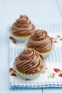 Mit Schokoladenbuttercreme überzogene Cupcakes auf Holztisch, Nahaufnahme - ECF000175