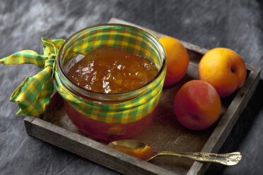 Glass bowl of apricot jam and apricots on wooden tray, close up - CSF019415