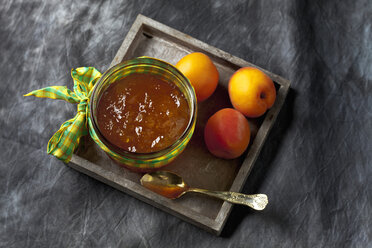 Glass bowl of apricot jam and apricots on wooden tray, close up - CSF019416