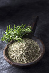 Grained rosemary in wooden spoon with rosemary herb, close up - CSF019421