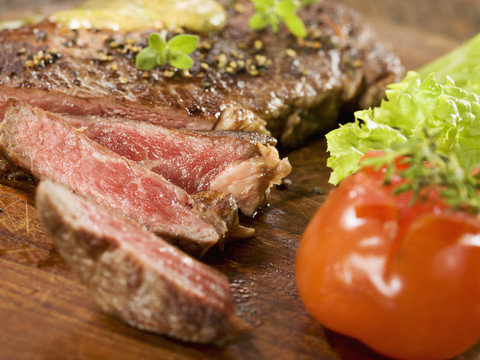 Gegrilltes Rib-Eye-Steak mit Kräutersauce auf Holz, lizenzfreies Stockfoto