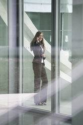 Germany, Berlin, Portrait of businesswoman talking on smart phone, smiling - FKIF000028